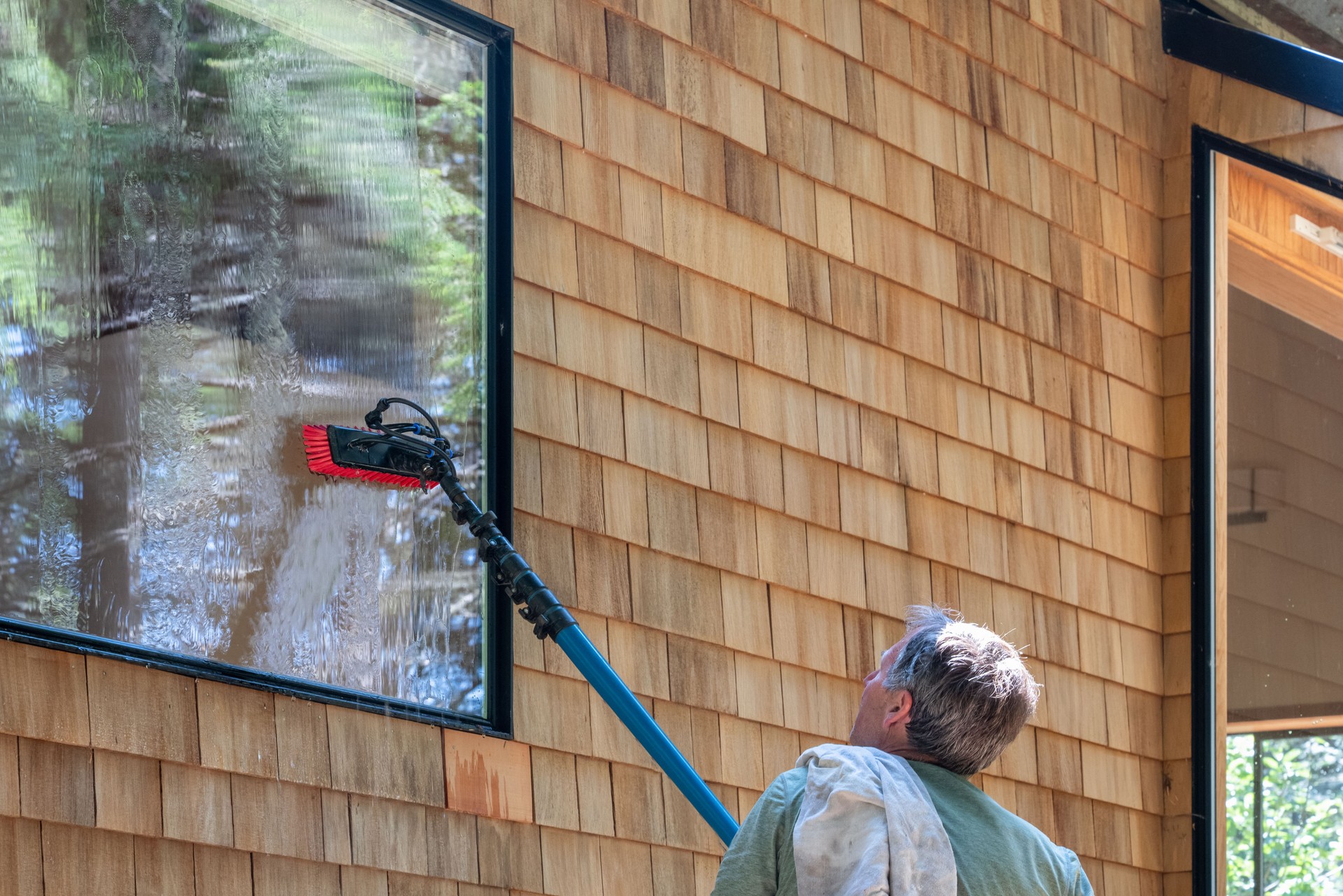 Man washing window with long pole and brush